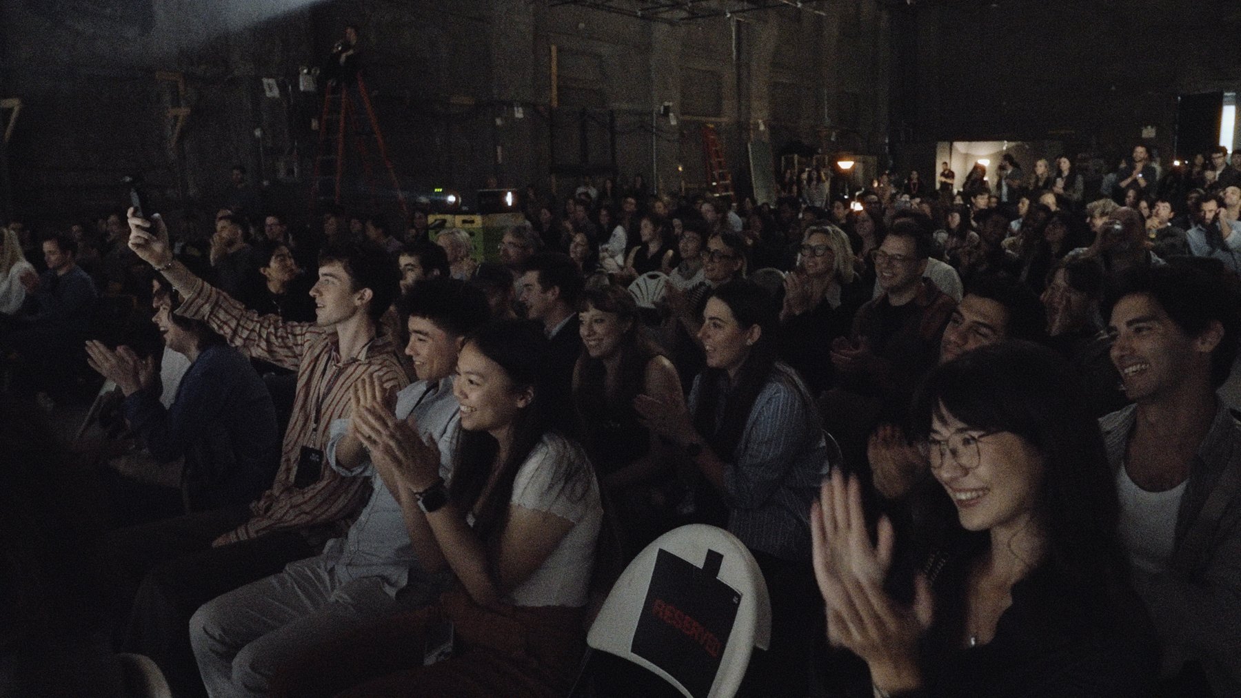 A packed Filmshow audience smiling and applauding after a performance