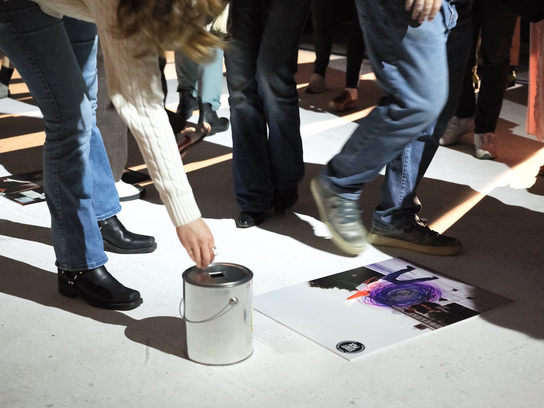 An audience member dropping a marble into a tin to vote for their favorite film