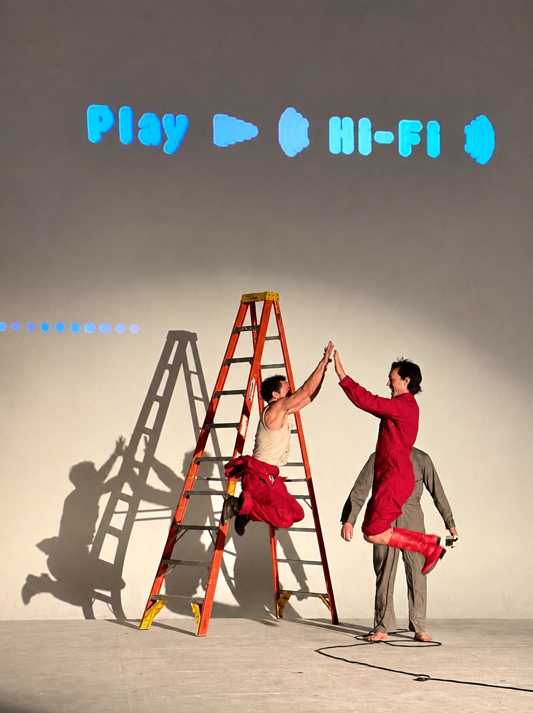 Filmshow performers high-fiving beside a ladder.